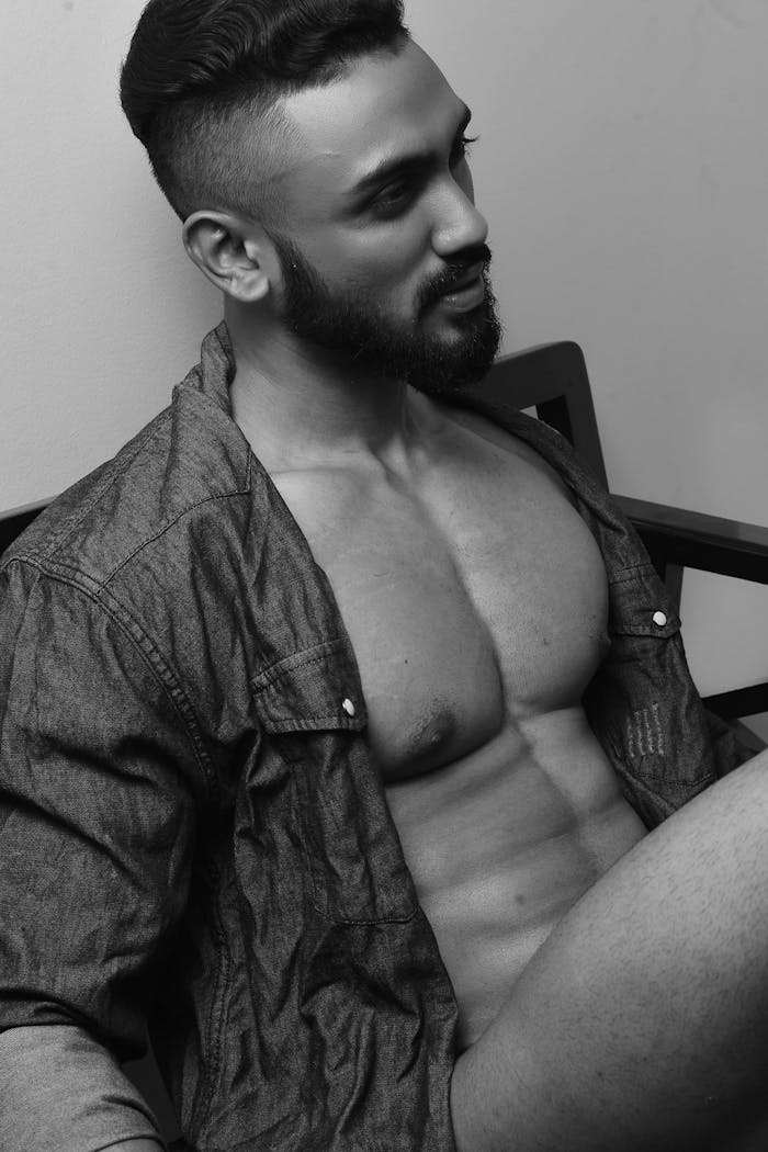 Stylish black and white portrait capturing a confident man with a muscular physique and a contemplative expression.