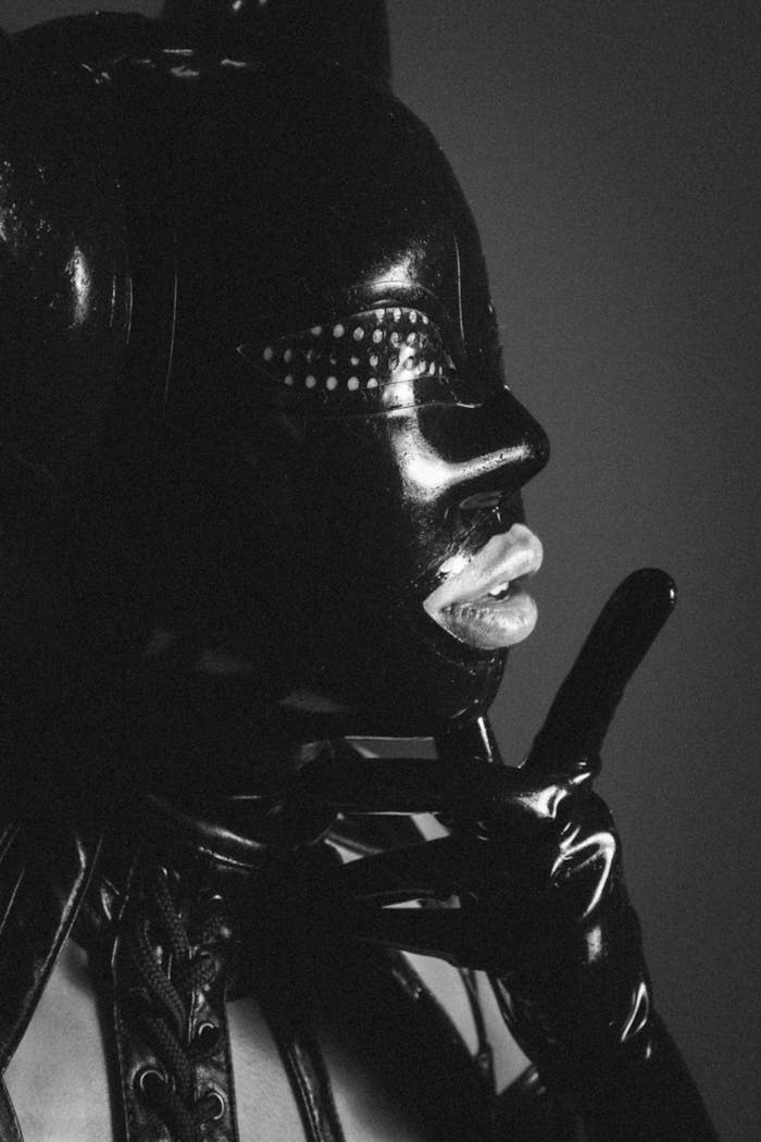 Dramatic black and white portrait of a person in a leather mask, showcasing surreal style.